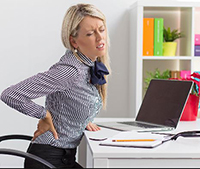 A woman with sciatica having pain while working at her desk