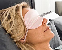 A woman trying to sleep during the day with a mask on