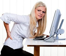 A woman not sitting correctly at her computer suffering with low back pain